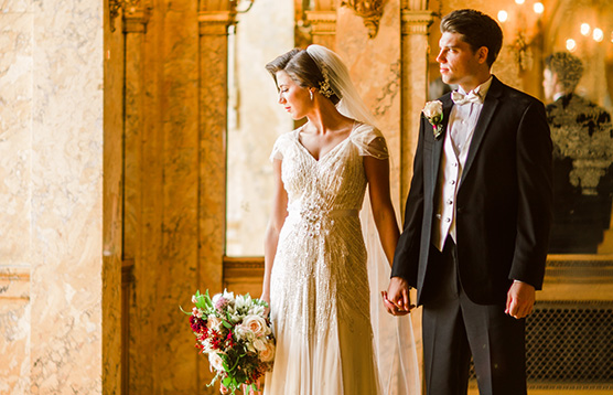 A bride and groom holding hands in front of an archway.